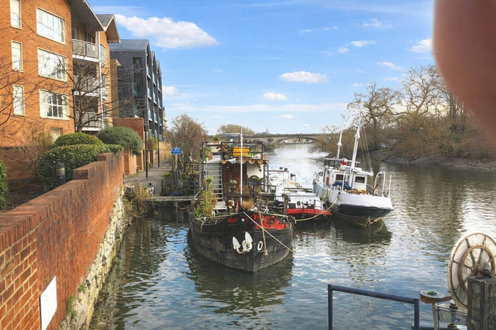 Boats moored on a London river with brick buildings