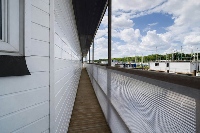 Narrow balcony next to white boat with marina view