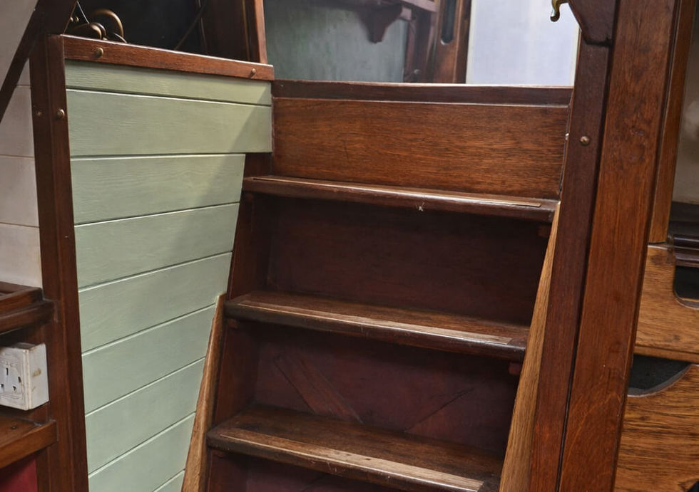 Steep wooden companionway stairs leading up to a boat's cabin, with a light green paneled wall on the left.