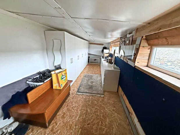 Long narrow room with white storage, wooden bench, window