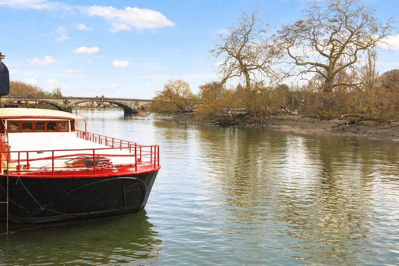Moored boat on a river, stone bridge in distance