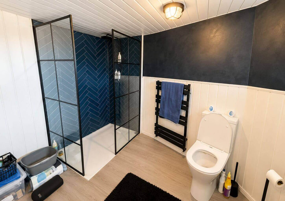 Modern bathroom with a black grid walk-in shower, blue herringbone tiles, and a white toilet.