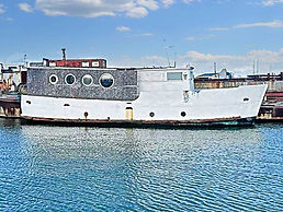 Sule Skerry boat with round portholes docked in calm blue water under a cloudy sky.