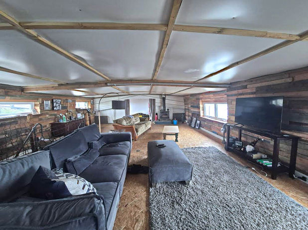 Living room with gray sofas, rug, TV, and wood ceiling.
