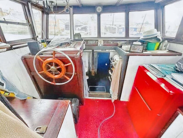 Interior view of a boat cabin with a steering wheel and windows