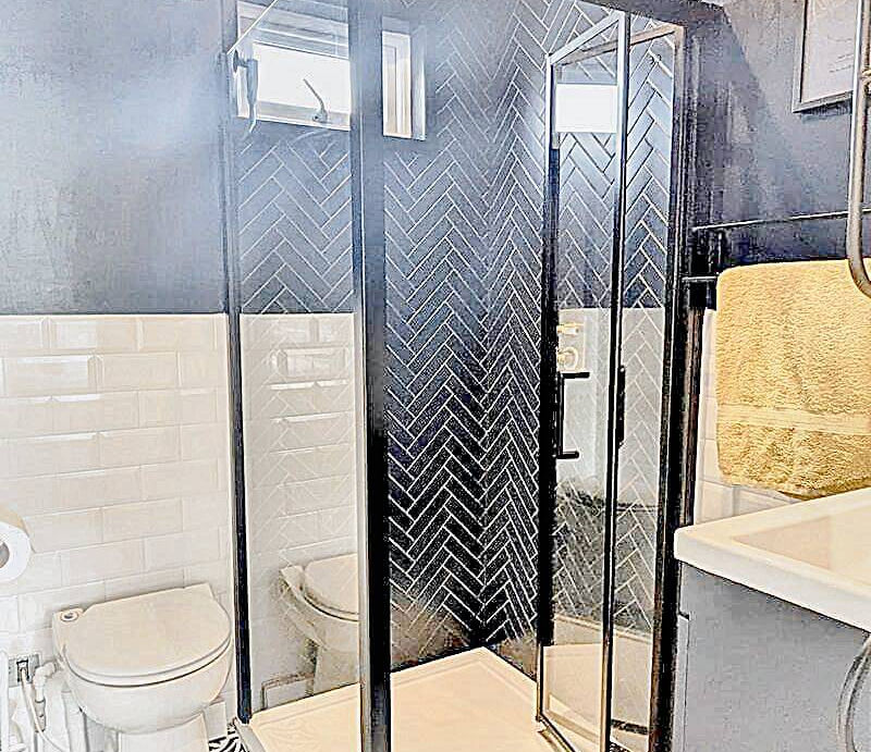 A clean bathroom featuring a shower and a toilet, with neutral-colored tiles and modern fixtures.