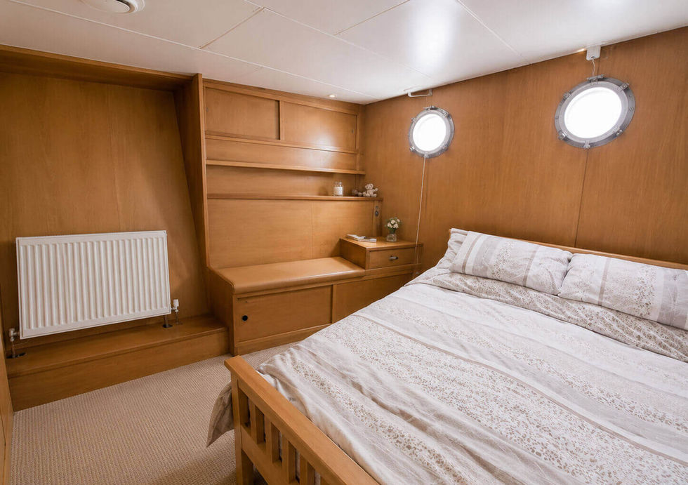 Bright wooden bedroom cabin with built-in shelving.