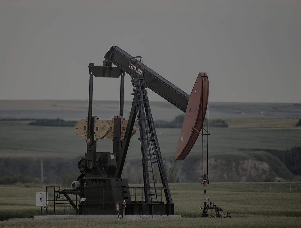 A pump jack sits in the middle of a Canola Field on the banks of the Red Deer River valley