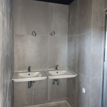 Deux lavabos blancs dans une salle de bain grise.