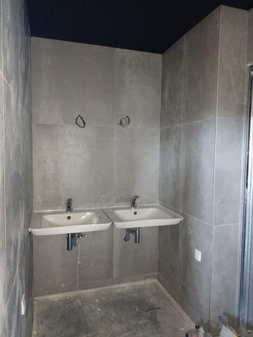 Deux lavabos blancs dans une salle de bain grise.