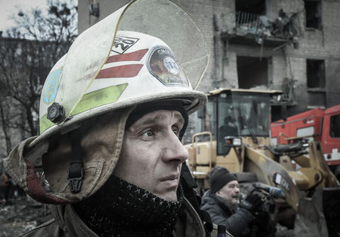 A man wearing a fireman's helmet standing in front of a building