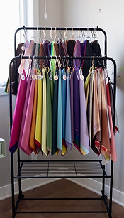 Set of color analysis drapes organized in seasons and rainbow order on a black rack