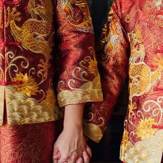 Two grooms holding hands in traditional Chinese wedding attire