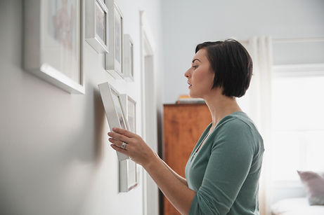 Lady Hanging professionally framed artwork onto her walls