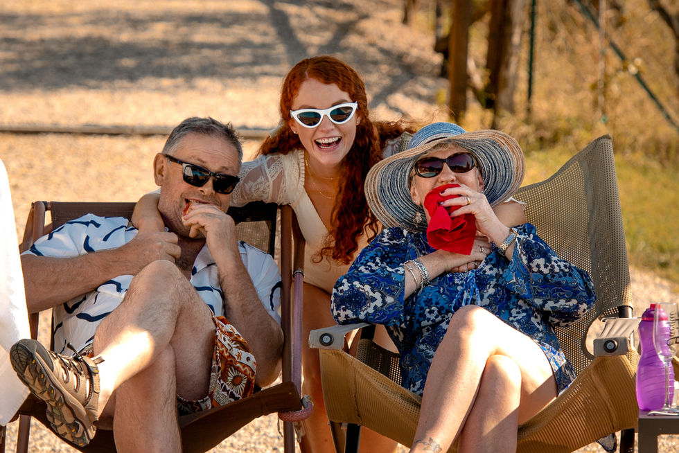 Three people smiling while sitting outside together wearing sunglasses. Jacqui and Jack.
