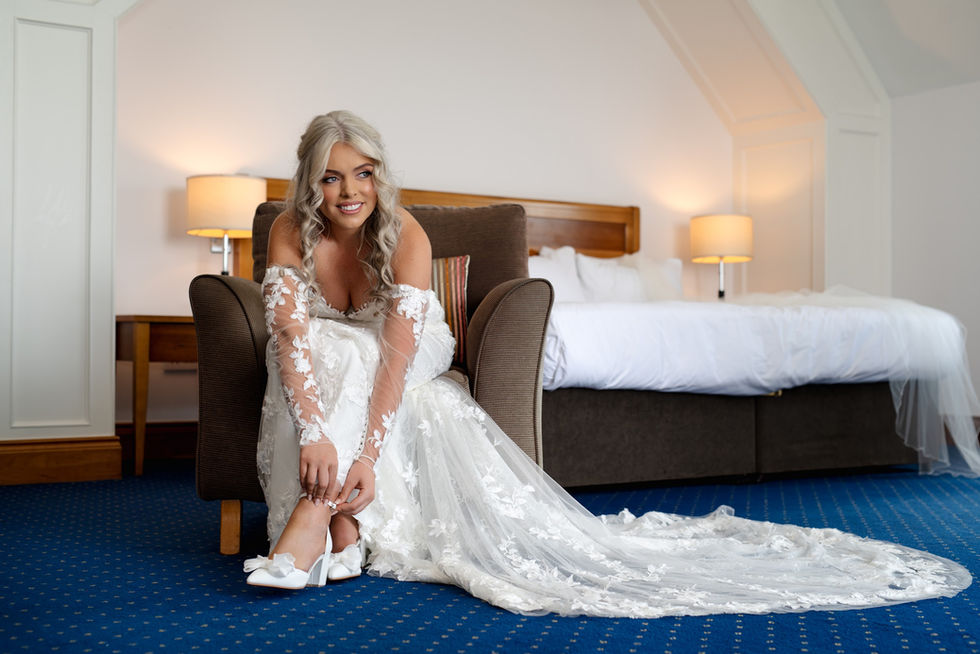 Bride in wedding dress seated on chair smiling before wedding ceremony
