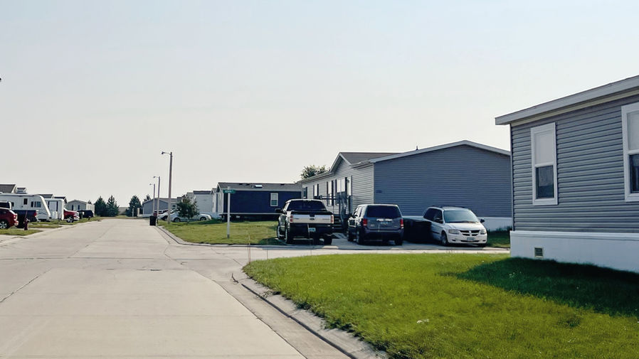 Mobile homes with green lawns and paved roads at Apple Creek Mobile Home Community in Bismarck, North Dakota.
