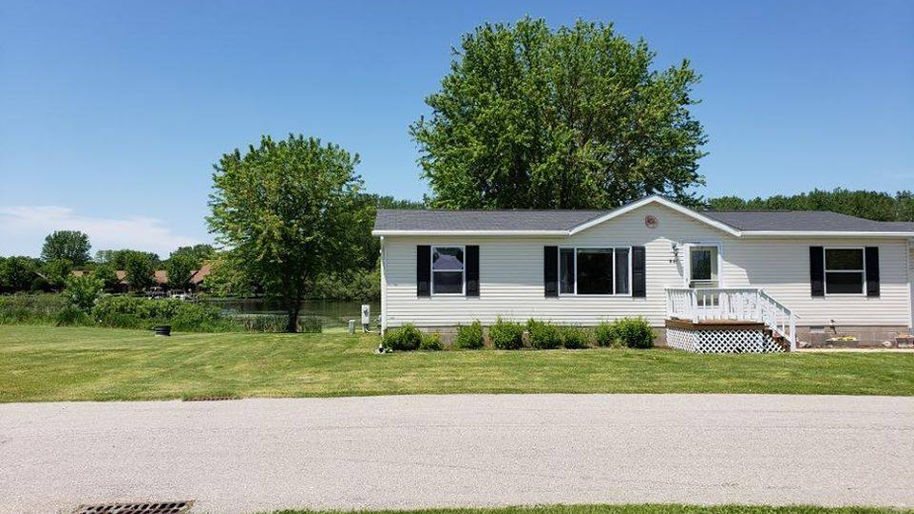 Street view on mobile home on green grass with trees in Riverlane Mobile Home Community located in Omro, WI.