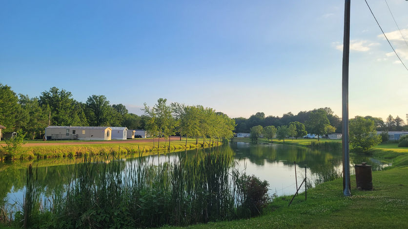 Beautiful water side view of Mediterranean Place Mobile Home Community at sunset surrounded by greenery.
