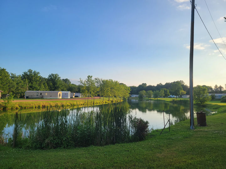 Beautiful water side view of Mediterranean Place Mobile Home Community at sunset surrounded by greenery.