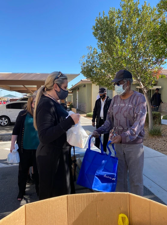 Employees handing out Thanksgiving turkey giveaway items to people with masks
