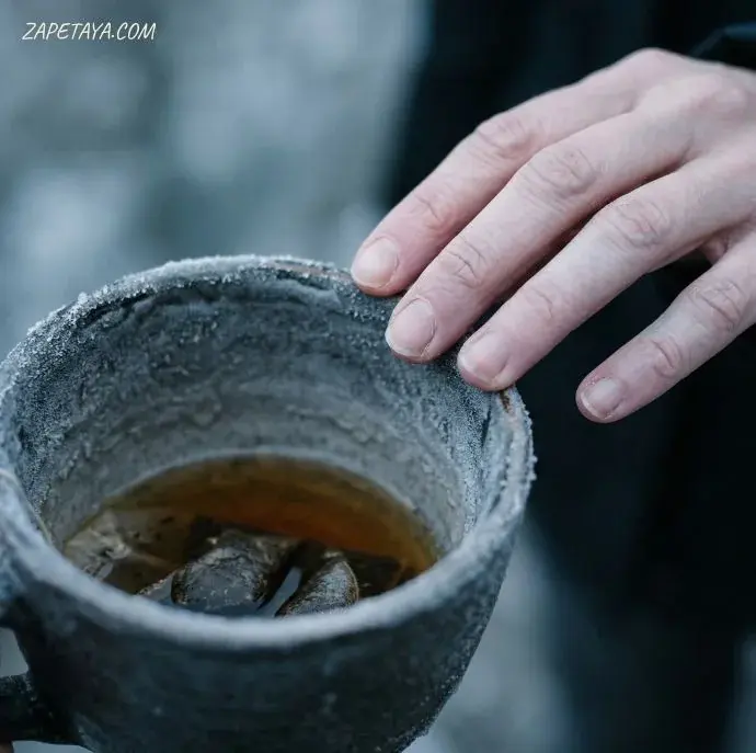 Ръка държи замръзнала чаша с лед и течност