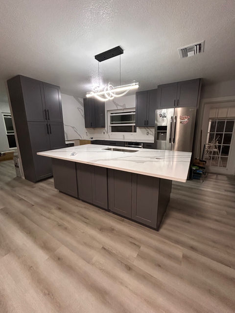 Modern kitchen remodel in a Central Florida home with dark gray shaker cabinets and Calacatta quartz countertops and backsplash.