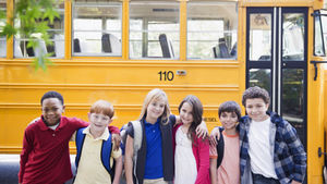 Children with backpacks standing in front of a yellow school bus, representing K–12 education expenses that can be covered by a 529 plan.