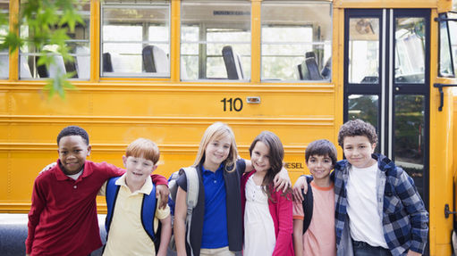 Children with backpacks standing in front of a yellow school bus, representing K–12 education expenses that can be covered by a 529 plan.