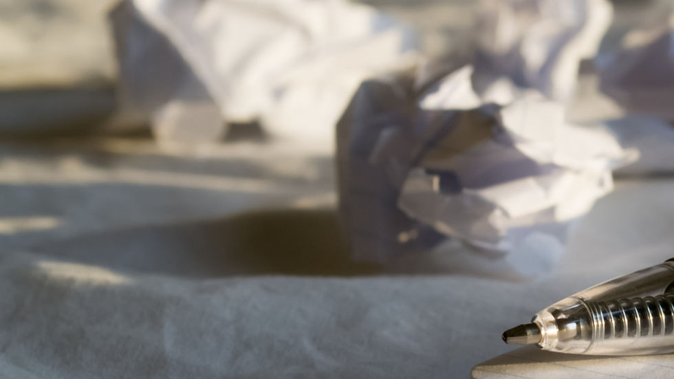 Pen on paper with crumpled sheets in the background, softly lit by natural light, creating a contemplative mood.