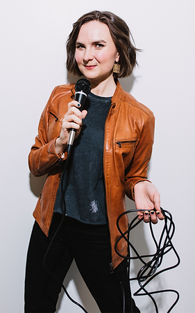 Sara Glancy- woman with brown hair holding a microphone