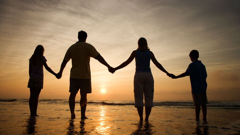 Family Holding Hands on Beach Watching sunset