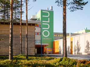 Çam ağaçları arasında yükselen modern Oulu Üniversitesi kampüs binası ve girişindeki ana tabela.