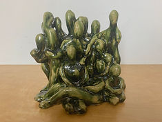 Ceramic piece of thirteen green figures standing next to each other.