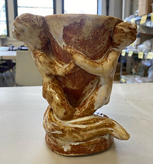Ceramic cup whose handle looks like two figures hugging.