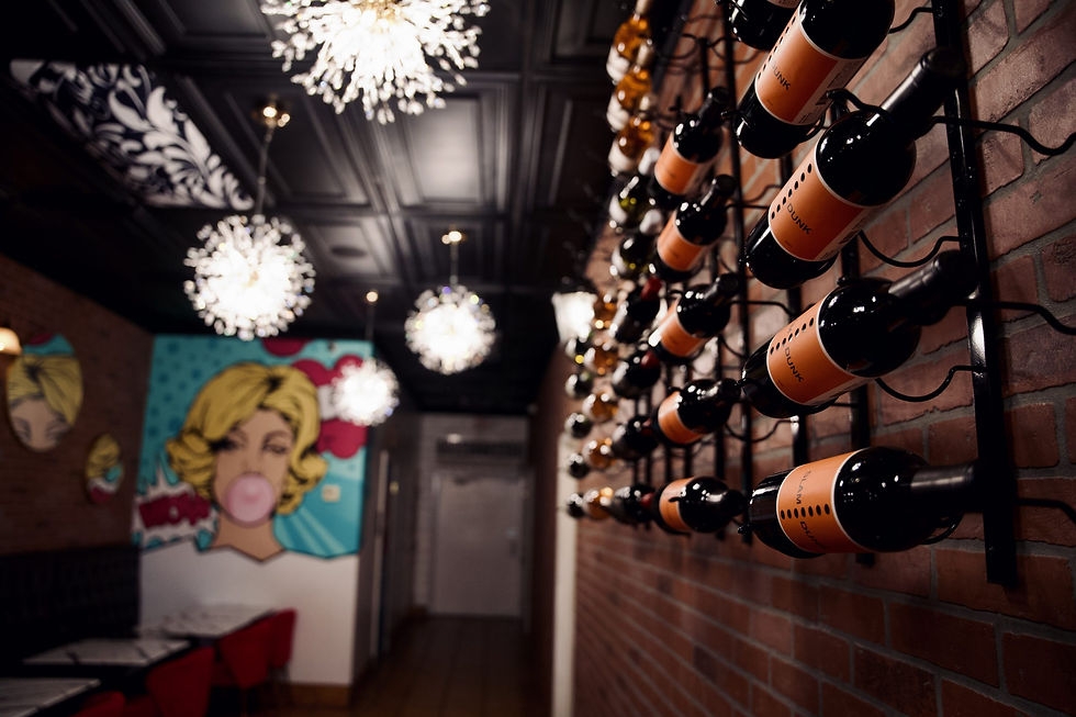 Wine bottles displayed on a brick wall inside Lady R Bistro, with colorful pop-art décor in the background.
