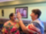Two West Valley Women Veterans members smiling and sharing a high-five at a community gathering.