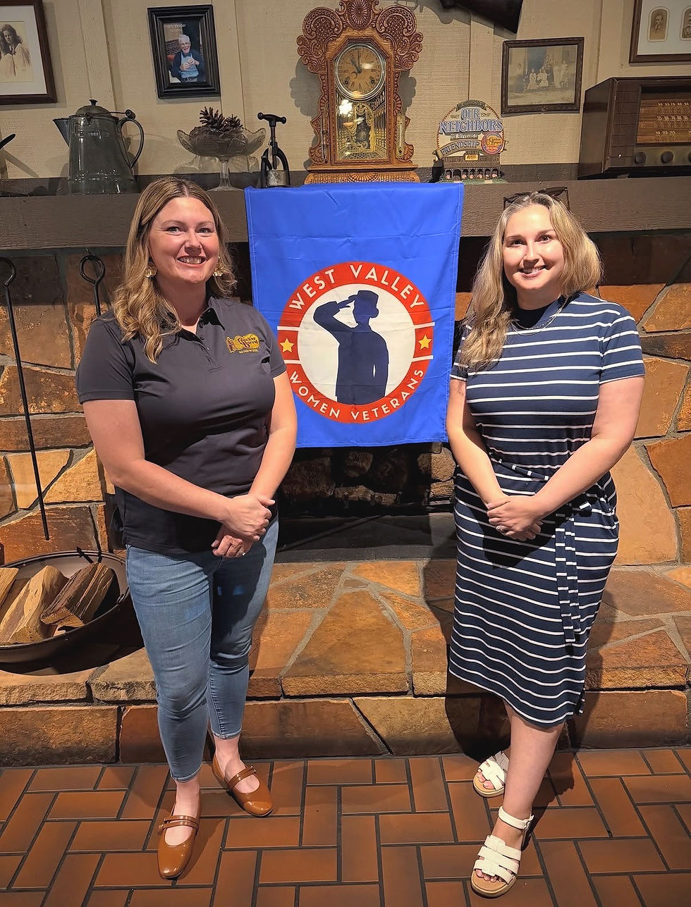 Two women standing beside a West Valley Women Veterans banner at a community gathering.