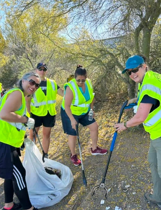 Four West Valley Women Veterans volunteers wearing safety vests during an outdoor community cleanup.