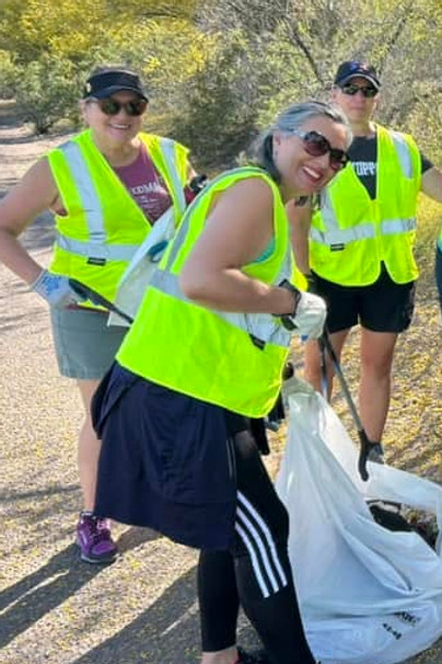 Three West Valley Women Veterans volunteers wearing safety vests during an outdoor community cleanup.