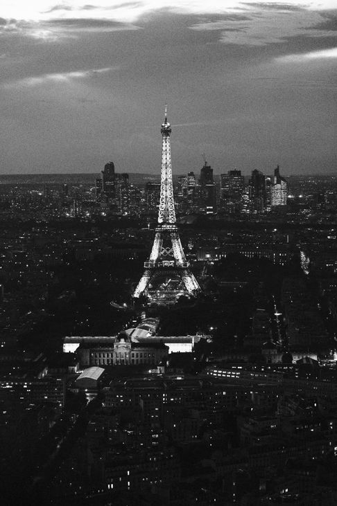 The Eiffel Tower illuminated at night, its lights radiating across the Parisian skyline, captured from the Montparnasse Tower.