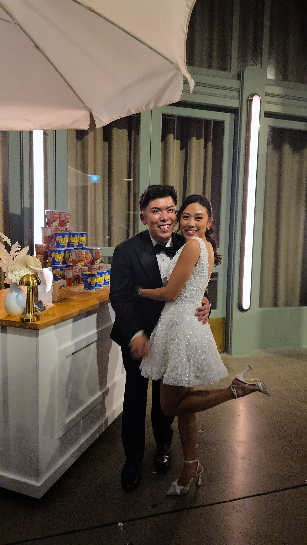 Bride and groom enjoying ramen from an interactive ramen cart at their wedding, sharing a warm and joyful moment with guests during the reception.