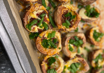 A platter of crispy baked potato skins, filled with melted cheddar cheese and bacon, and topped with chopped green onions.