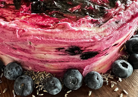 A gluten-free blueberry lavender lemon cake topped with fresh blueberries and lavender sprigs.