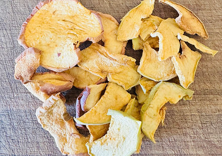 Crispy homemade oven-dried apple chips arranged on a wood cutting board, showing thinly sliced apples with golden edges.