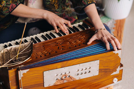 Hands of a woman sitting on the floor and playing the harmonium during the practice of kun