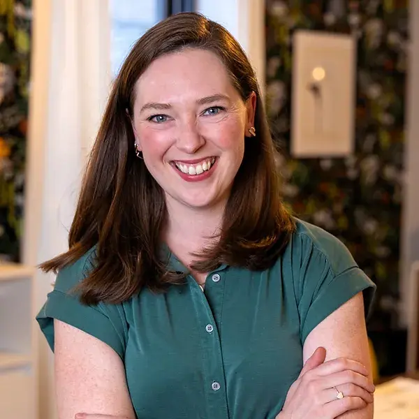 Emily Jackson smiles broadly, wearing a teal green button-up