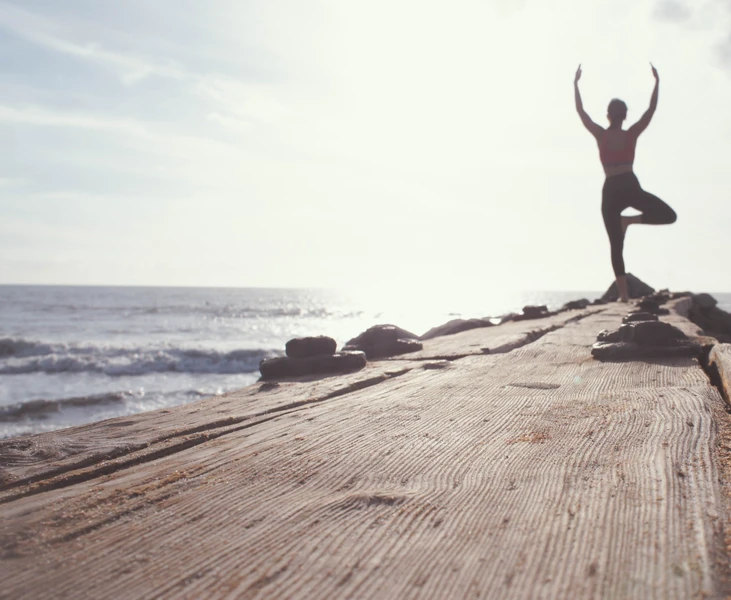 Tree pose at the end of a dock with a beautiful sky in the background. Nature based Yoga, eco-psychology