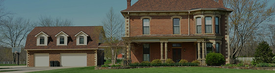 Brick house with attached garage and green front lawn on a sunny day