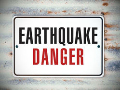 Earthquake danger sign in bold black and red on a rusty metal background, warning of hazardous conditions.